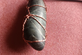 Pilkai baltos spalvos natūraliai paplitęs akmuo apipintas perpintu variu